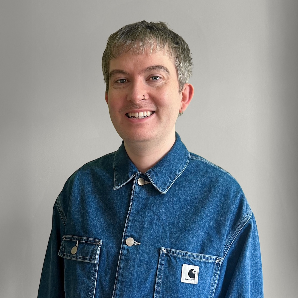 A photo of me in a blue denim jacket, against a lime green background